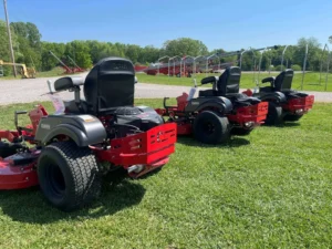 Three red lawn mowers on grass.
